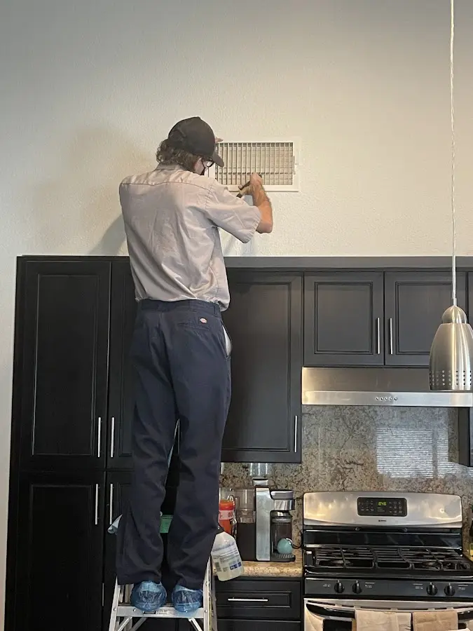 Technician inspecting an air vent during HVAC service in Oldsmar